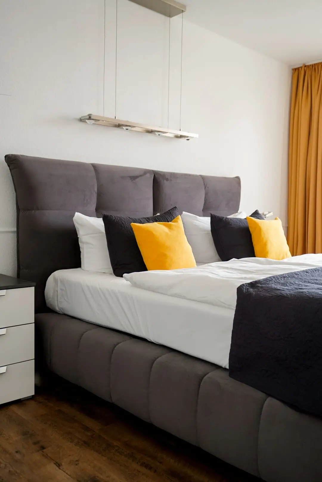 Doppelbett mit gepolstertem Kopfteil und gelben Kissen