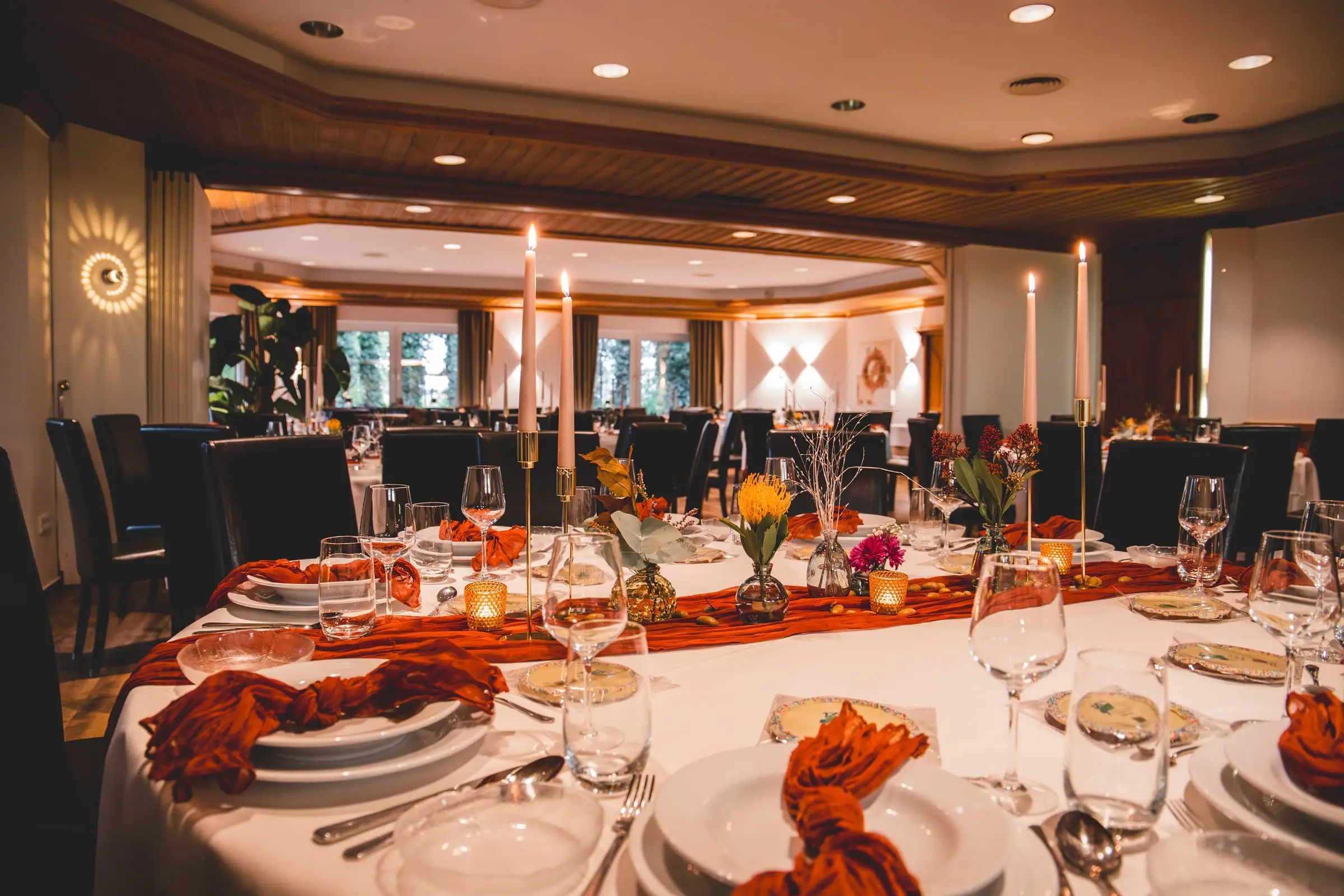 Lange Festtafel mit hohen Kerzen und Blumen im Saal