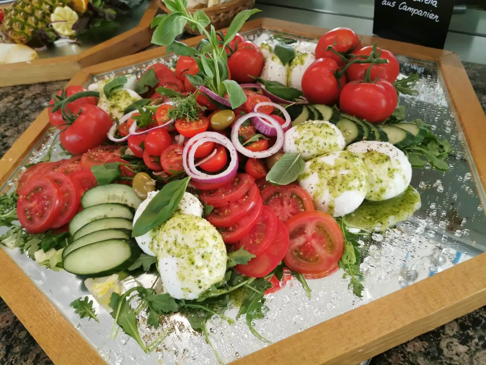 Mozzarellakugeln in Kräuteröl, dazu Tomaten und Gurken