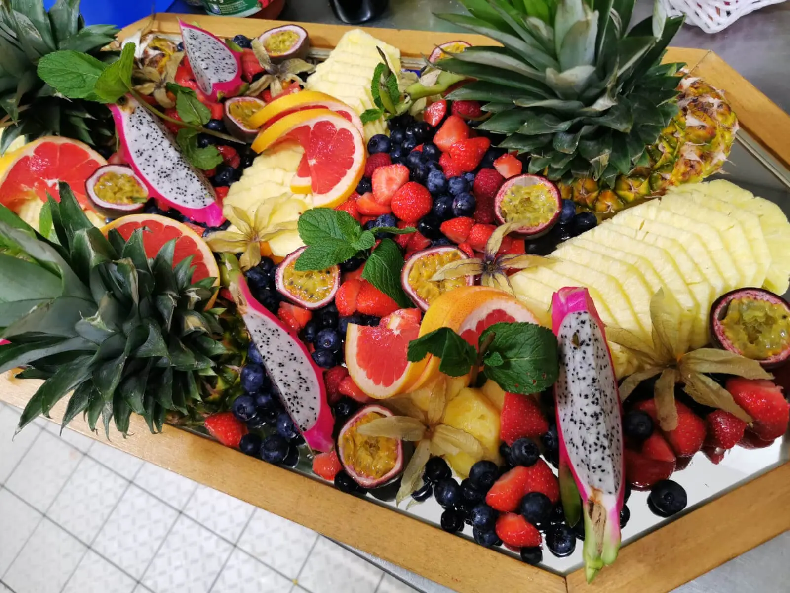 Üppige Obstplatte mit Ananaskronen, Grapefruit und frischer Minze