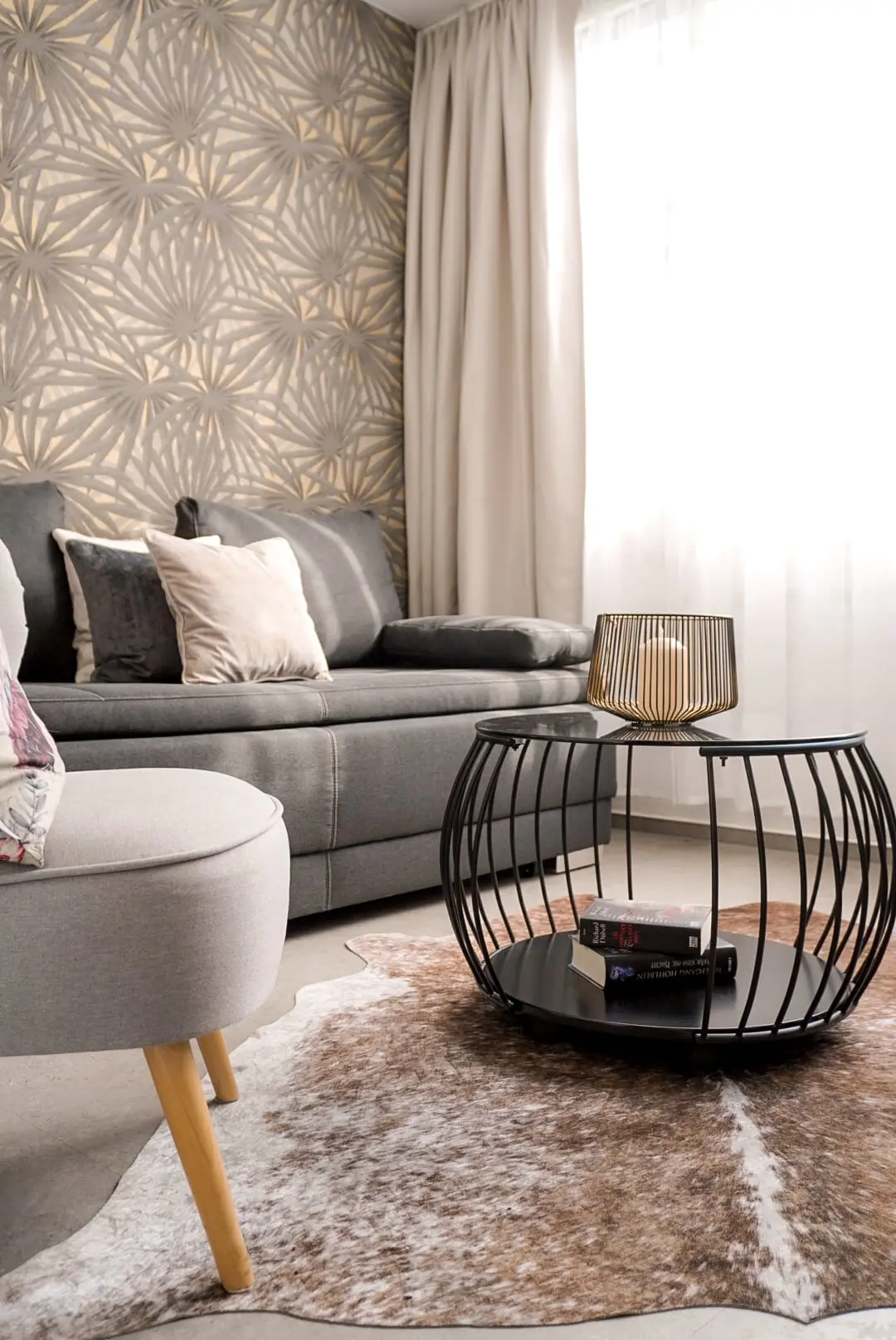 Der Wohnbereich der Suite: graues Sofa am Fenster, Fellteppich und runder Beistelltisch