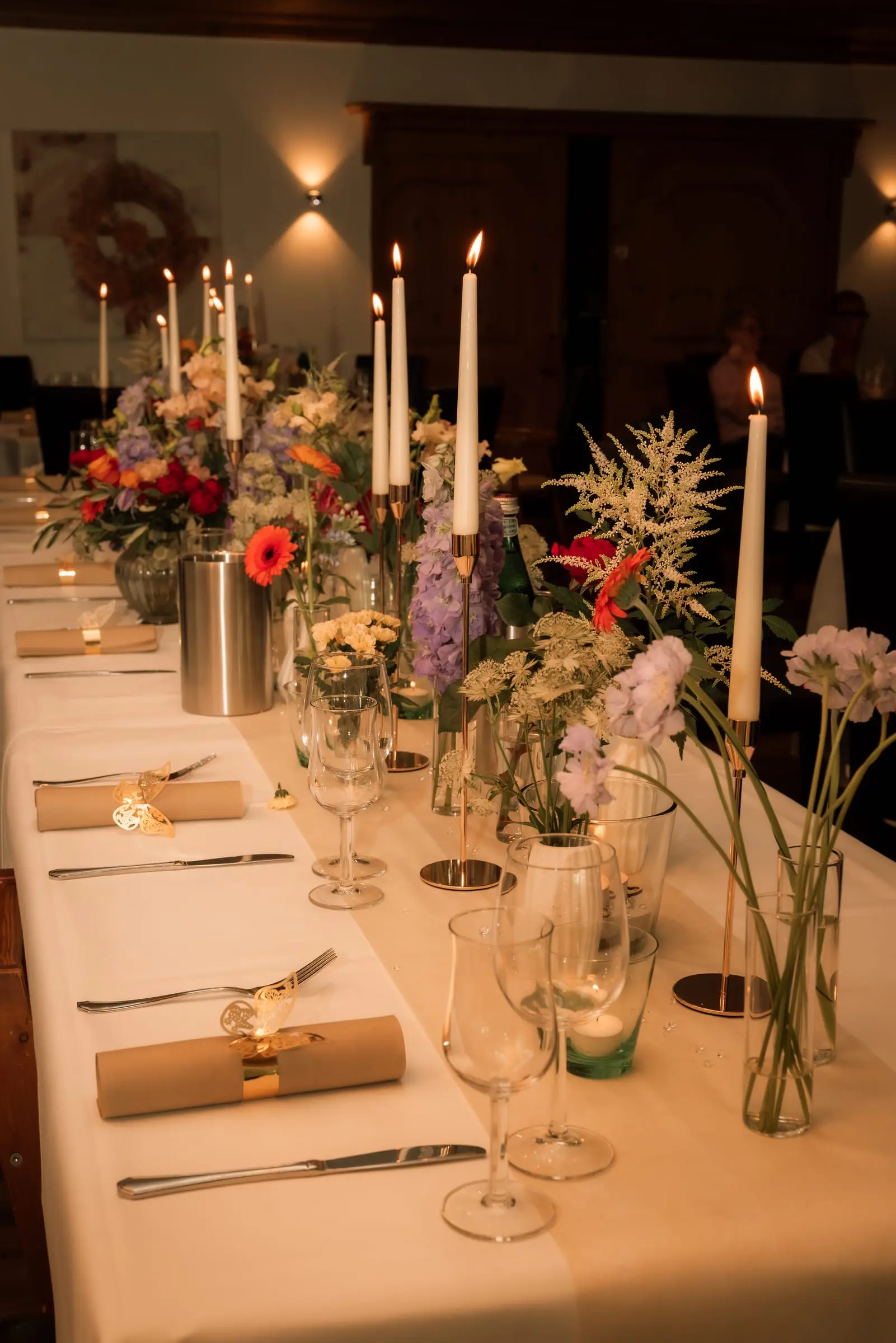 Gedeckte Tafel im Kerzenschein, mit Blumen und Servietten