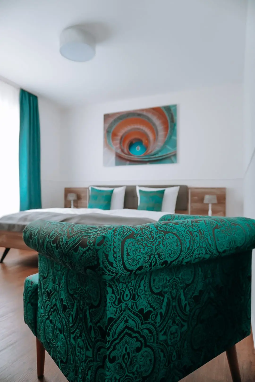 Doppelzimmer mit grünem Ornamentsessel und türkisen Kissen